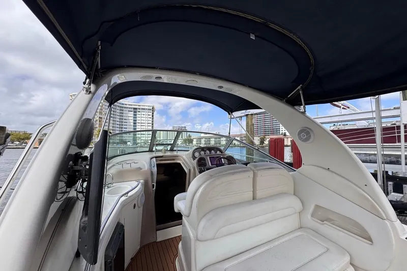 Slide: The Image of 2005 Sea Ray 300 Sundancer boat interior with helm and seating, docked at marina. - 13