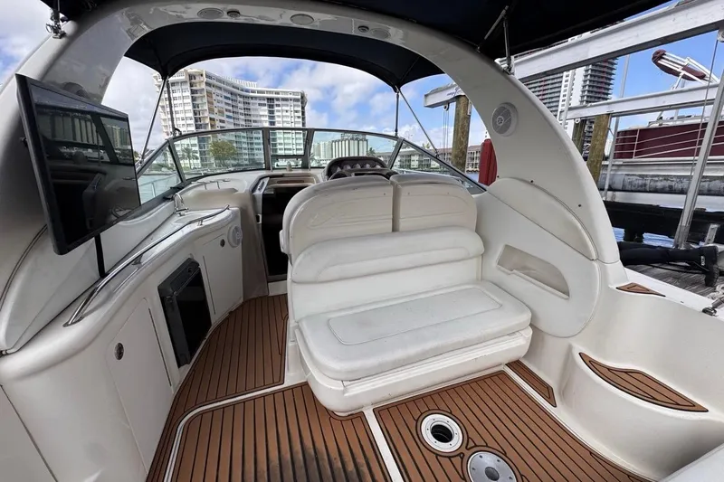 Slide: The Image of 2005 Sea Ray 300 Sundancer interior with white seating and wood flooring at a marina. - 14