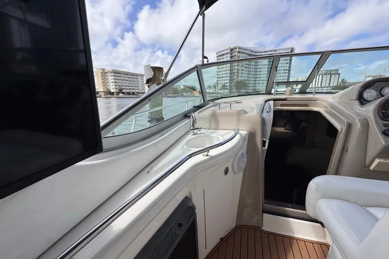 Slide: The Image of 2005 Sea Ray 300 Sundancer boat interior with sink, seating, and cityscape view. - 19