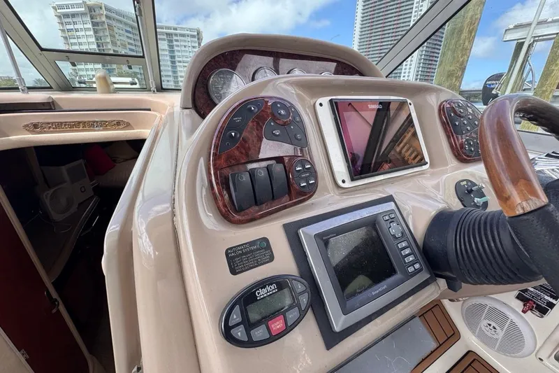 Slide: The Image of 2005 Sea Ray 300 Sundancer helm with navigation controls and wood accents. - 22