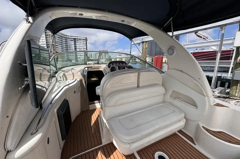 Slide: The Image of 2005 Sea Ray 300 Sundancer boat interior with seating and dashboard, docked at marina. - 29