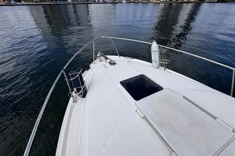 Slide: The Image of 2005 Sea Ray 300 Sundancer boat deck on calm water, featuring railings and hatch. - 41