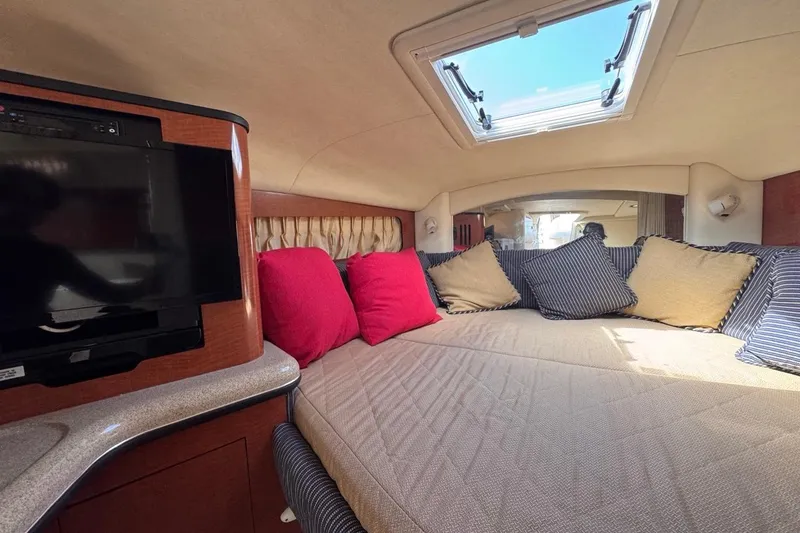 Slide: The Image of 2005 Sea Ray 300 Sundancer cabin interior with cozy bedding and TV. - 59