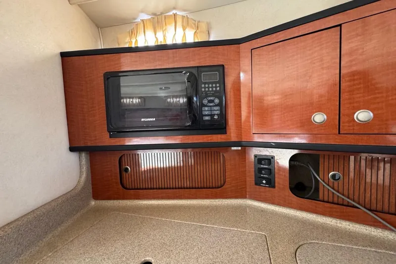 Slide: The Image of 2005 Sea Ray 300 Sundancer interior with microwave and wooden cabinetry. - 63