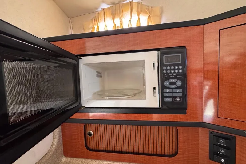 Slide: The Image of Microwave in 2005 Sea Ray 300 Sundancer boat interior, featuring wood cabinetry. - 64