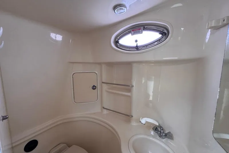 Slide: The Image of 2005 Sea Ray 300 Sundancer bathroom with sink, porthole, and storage. - 76