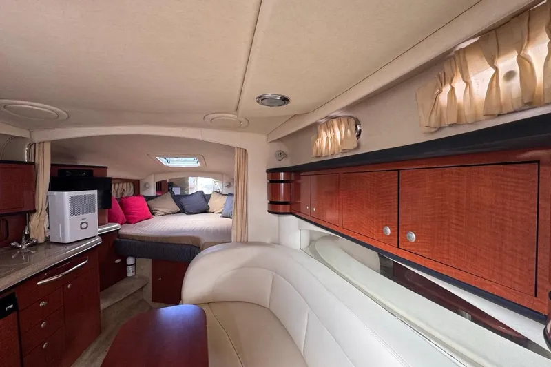 Slide: The Image of Interior of 2005 Sea Ray 300 Sundancer, featuring cozy cabin with bed, seating, and kitchenette. - 77