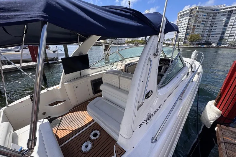 Slide: The Image of 2005 Sea Ray 300 Sundancer boat docked, featuring spacious seating and a canopy. - 8