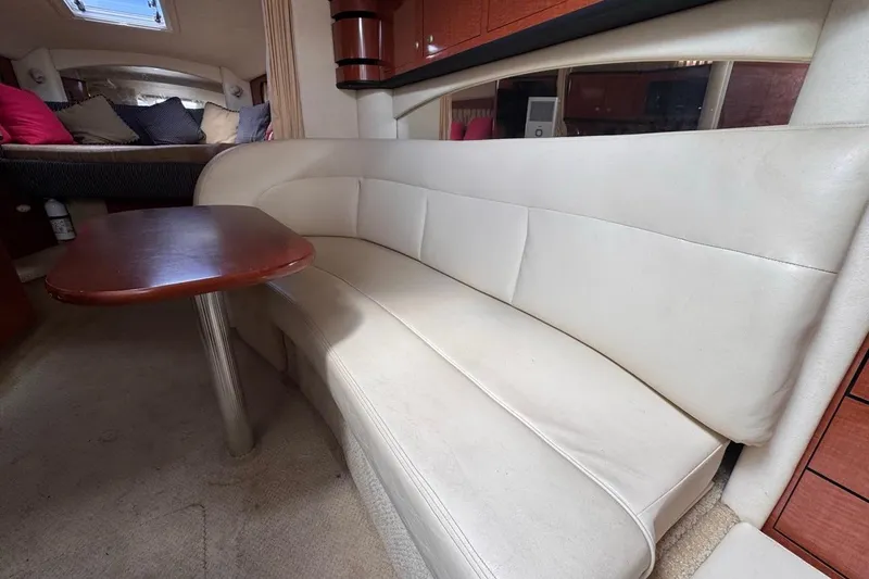 Slide: The Image of Interior of 2005 Sea Ray 300 Sundancer with white leather seating and wooden table. - 85