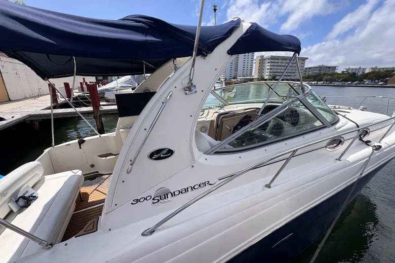 Slide: The Image of 2005 Sea Ray 300 Sundancer boat docked, featuring sleek design and blue canopy. - 9