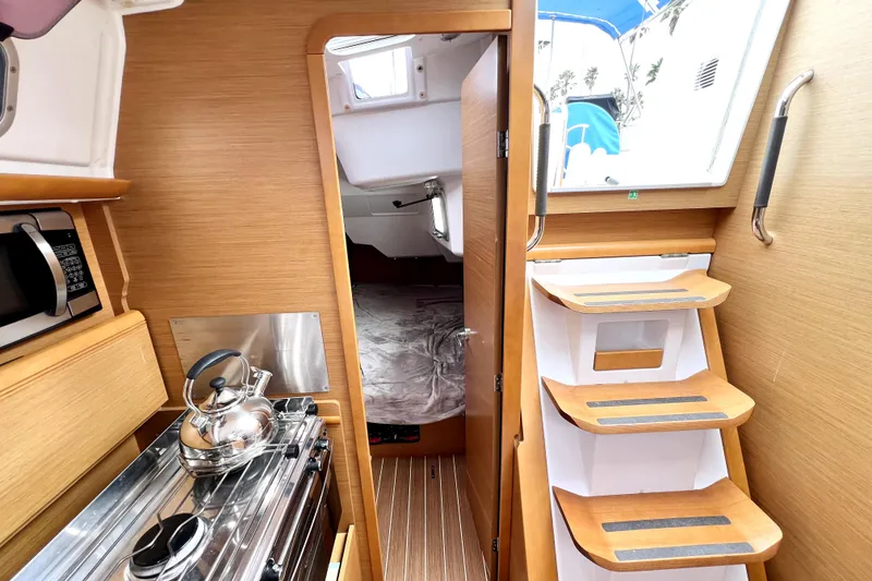 Slide: The Image of 2014 Jeanneau Sun Odyssey 379 yacht kitchen with stove, microwave, and wooden cabinetry. - 37