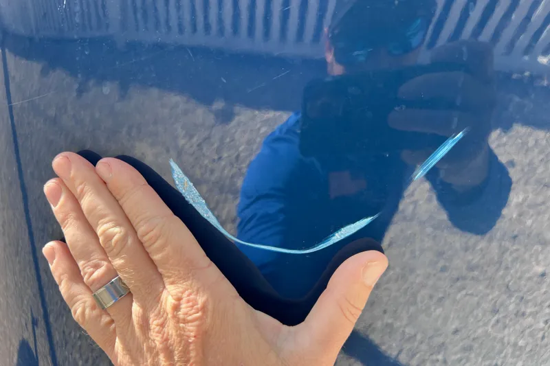 Slide: The Image of Hand inspecting scratch on 2021 Sea Ray SDX 270 Outboard boat hull. - 8