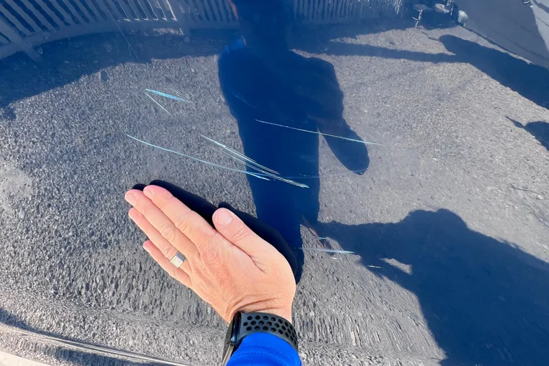 Slide: The Image of Hand inspecting scratches on 2021 Sea Ray SDX 270 Outboard boat surface. - 9