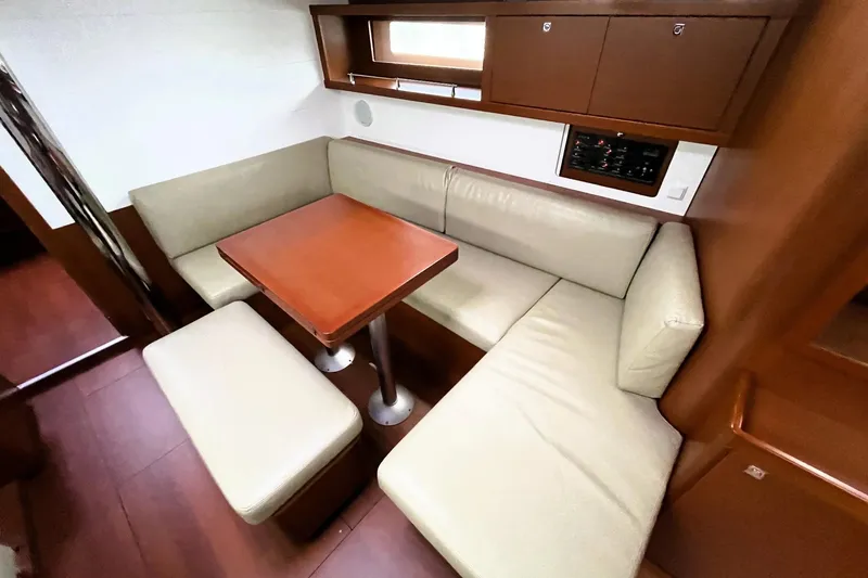 Slide: The Image of 2018 Beneteau Oceanis 45 interior with beige seating and wooden table. - 38