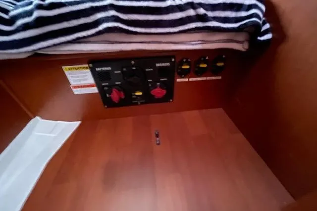 Slide: The Image of Electrical panel inside 2018 Beneteau Oceanis 45 yacht cabin with striped blanket above. - 48