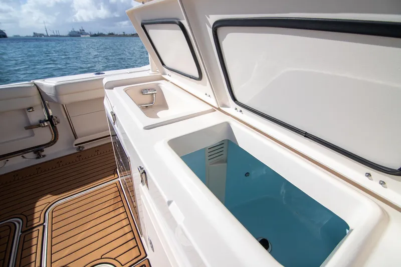 Slide: The Image of 2023 Grady-White Canyon 326 boat interior with open storage compartment, docked by the sea. - 11