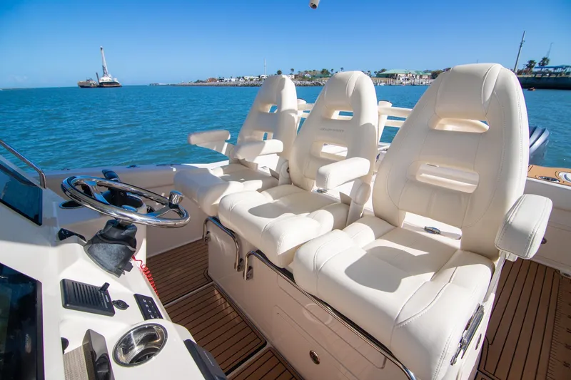 Slide: The Image of 2023 Grady-White Canyon 326 boat interior with luxurious white seating and steering wheel. - 12