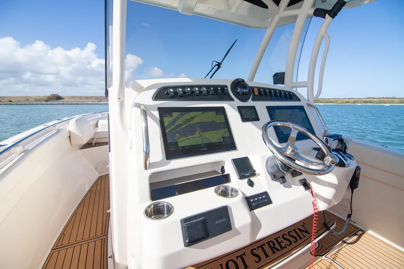 Slide: The Image of 2023 Grady-White Canyon 326 boat dashboard with navigation screens and steering wheel. - 15