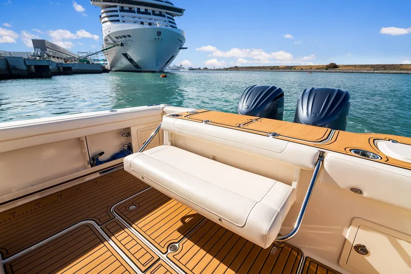 Slide: The Image of 2023 Grady-White Canyon 326 boat with dual engines, docked near a large cruise ship. - 7