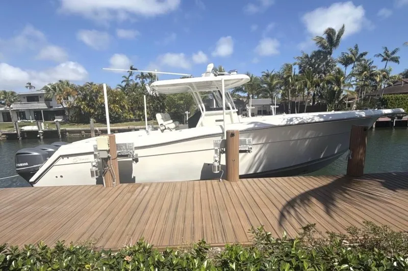 The Image of 2014 Stamas 390 Tarpon boat docked by a wooden pier, surrounded by palm trees. - 1