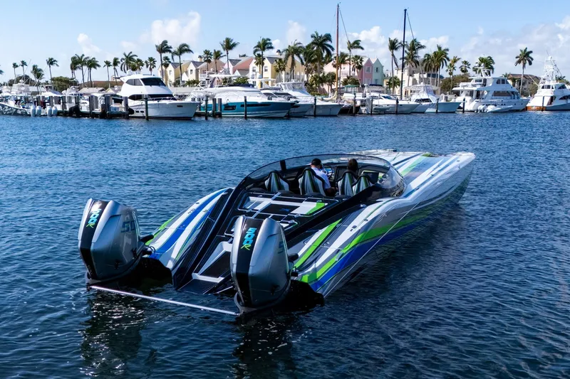Slide: The Image of 2022 MTI 390X powerboat with vibrant stripes docked in a marina, surrounded by yachts. - 3