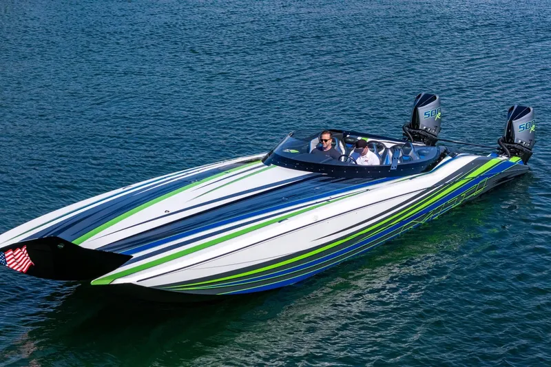 Slide: The Image of 2022 MTI 390X speedboat with vibrant blue and green stripes on calm water. - 34