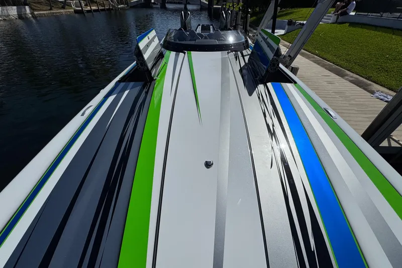 Slide: The Image of 2022 MTI 390X boat with vibrant green, blue, and gray stripes docked by a canal. - 44