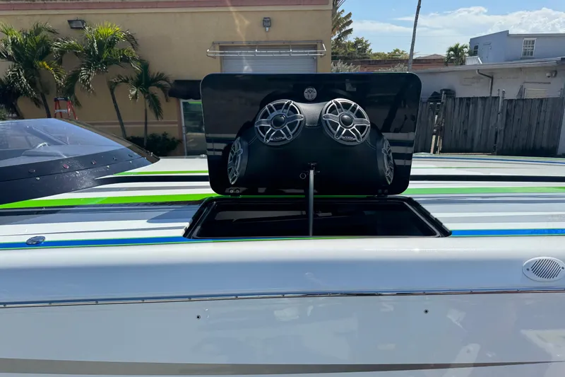 Slide: The Image of 2022 MTI 390X boat with vibrant green, blue, and gray stripes docked by the water. - 45