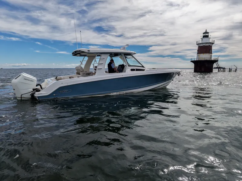 Slide: The Image of A 2027 Boston Whaler 350 Realm cruising on calm waters near a lighthouse. - 31