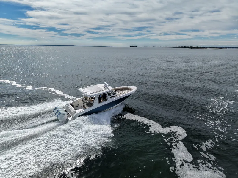 Slide: The Image of A 2027 Boston Whaler 350 Realm speeds across open water under a cloudy sky. - 32