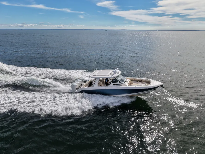 Slide: The Image of A 2027 Boston Whaler 350 Realm speeds across open sea under a blue sky. - 33