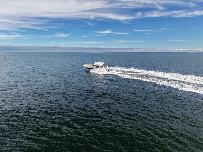 Slide: The Image of A 2027 Boston Whaler 350 Realm speeds across open sea under a clear sky. - 2