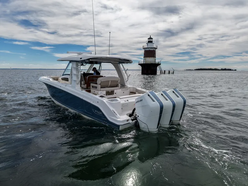 Slide: The Image of A 2027 Boston Whaler 350 Realm on calm waters near a lighthouse. - 1