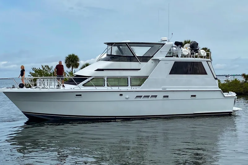 The Image of 1999 Hatteras 52 Cockpit Motor Yacht on calm water, with people on deck. - 1