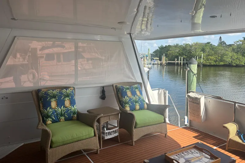 Slide: The Image of 1999 Hatteras 52 Cockpit Motor Yacht interior with tropical-themed seating and waterfront view. - 17