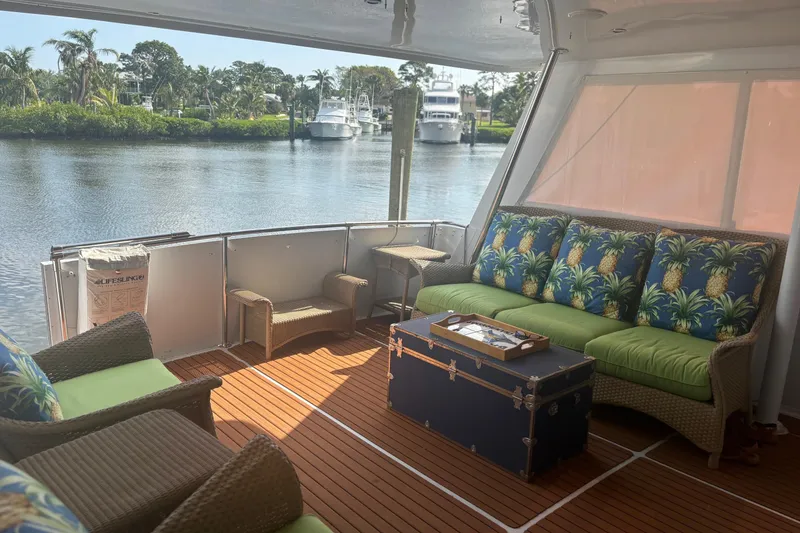 Slide: The Image of 1999 Hatteras 52 Cockpit Motor Yacht interior with tropical-themed seating and waterfront view. - 18