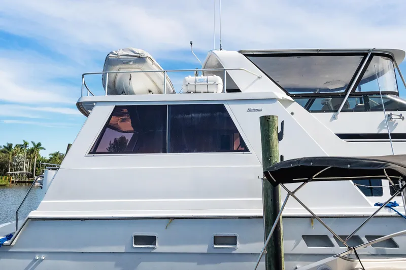 Slide: The Image of 1999 Hatteras 52 Cockpit Motor Yacht docked, featuring sleek design and spacious upper deck. - 3