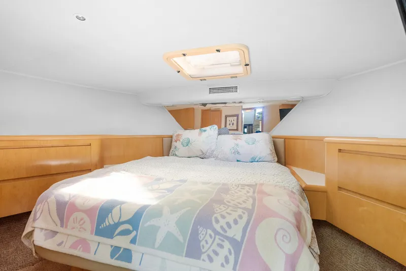 Slide: The Image of 1999 Hatteras 52 Cockpit Motor Yacht bedroom with cozy bedding and natural light. - 32