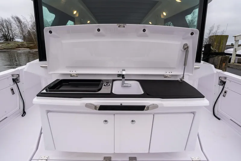 Slide: The Image of 2027 Axopar 38 Cross Cabin boat kitchen with sink and storage compartments. - 11