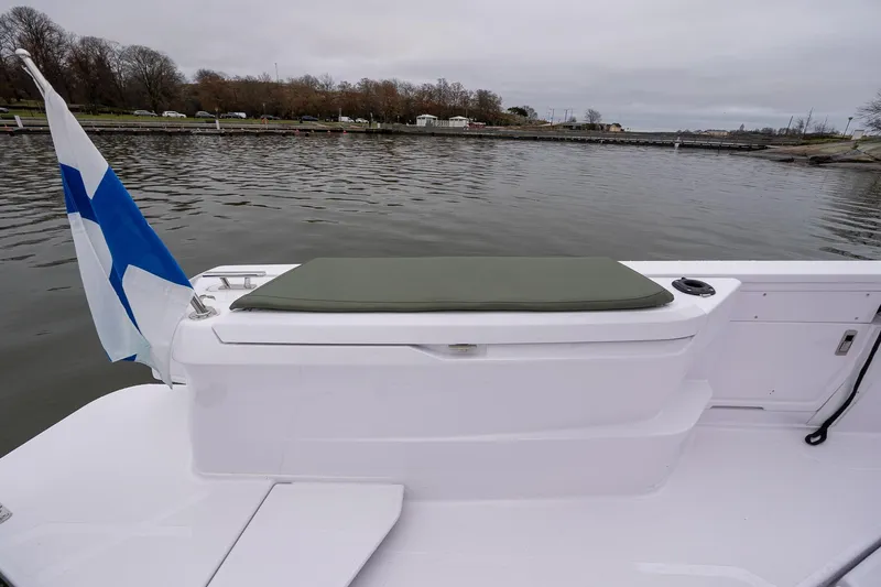 Slide: The Image of 2027 Axopar 38 Cross Cabin boat with flag, docked on calm water. - 18