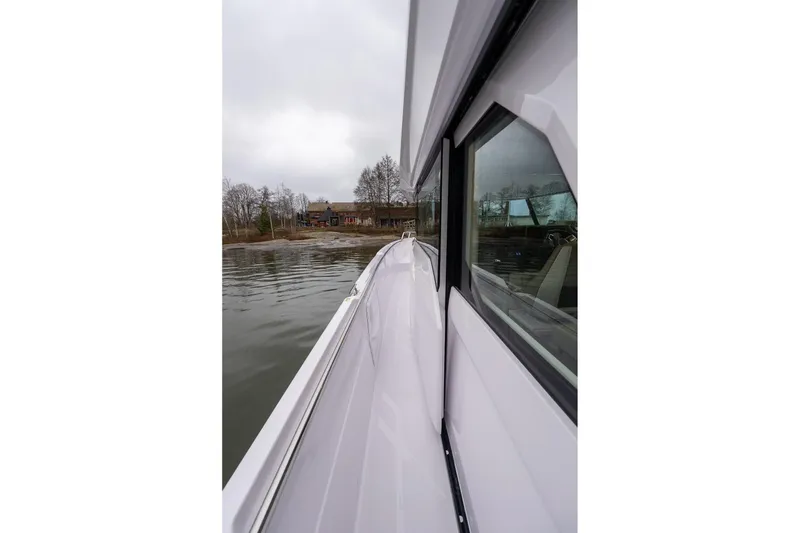 Slide: The Image of 2027 Axopar 38 Cross Cabin boat on calm water near a shoreline. - 23