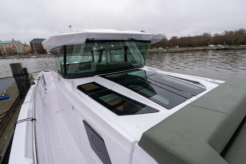 Slide: The Image of 2027 Axopar 38 Cross Cabin boat docked by a calm waterfront. - 33