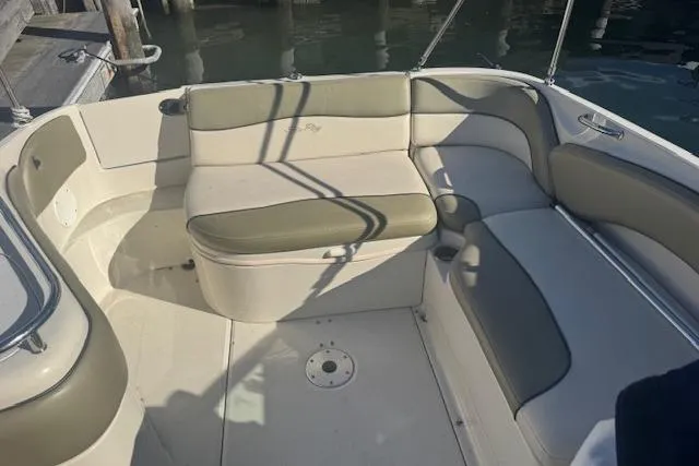 Slide: The Image of 2005 Sea Ray 240 Sundeck interior with beige and green seating, docked by water. - 11