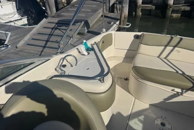 Slide: The Image of 2005 Sea Ray 240 Sundeck interior with seating and sink, docked by wooden pier. - 10
