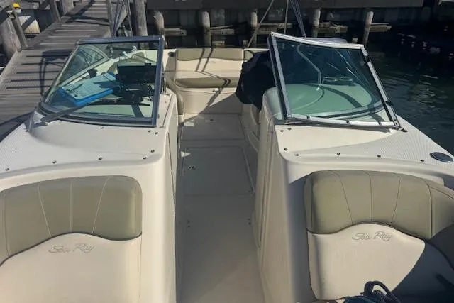 Slide: The Image of 2005 Sea Ray 240 Sundeck boat interior with dual windshields and seating, docked by a pier. - 6