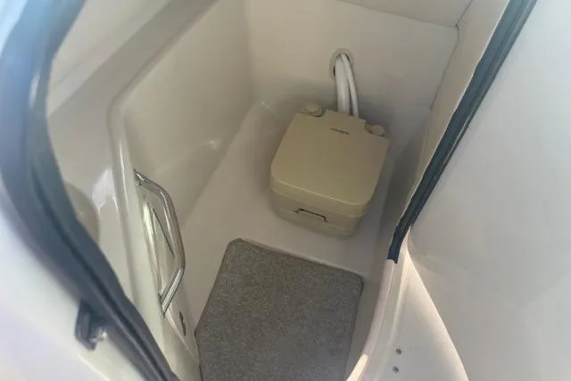 Slide: The Image of 2005 Sea Ray 240 Sundeck interior with portable toilet and carpeted floor. - 7