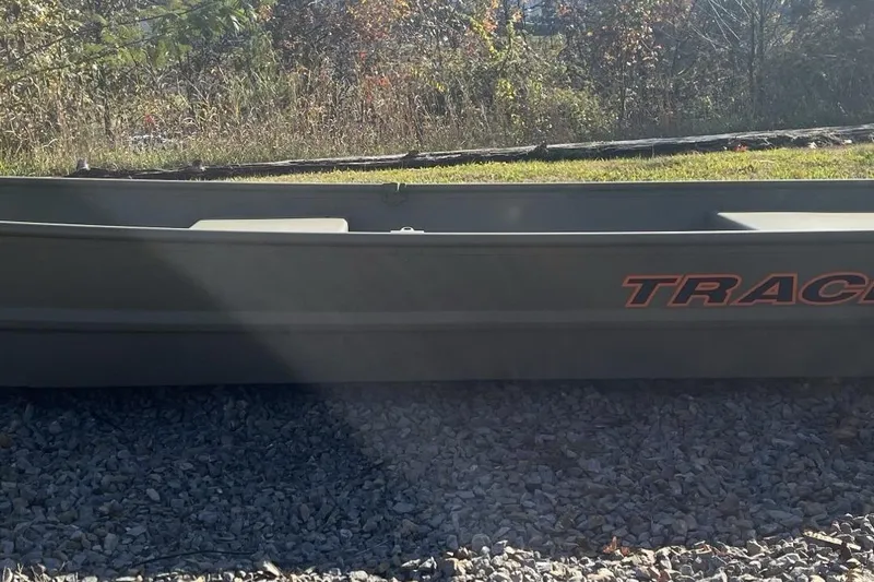 The Image of 2026 Tracker Grizzly 14 Jon boat on gravel, surrounded by grass and trees. - 0