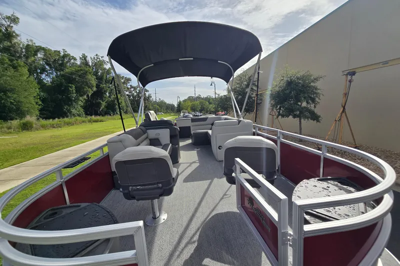 Slide: The Image of 2026 Sun Tracker SportFish 20 DLX pontoon boat with canopy and seating, parked outdoors. - 58