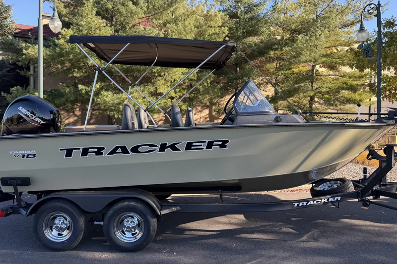 Slide: The Image of 2026 Tracker Targa V-18 WT boat on trailer, parked outdoors with trees in background. - 86
