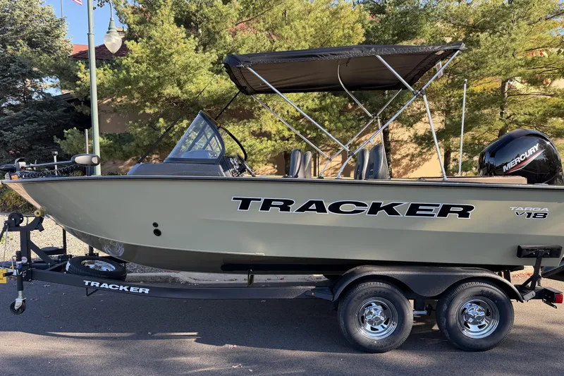 Slide: The Image of 2026 Tracker Targa V-18 WT boat on trailer, outdoors with trees in background. - 87